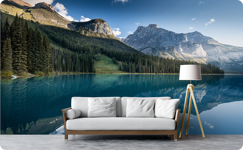 Turquoise lake and mountain wallpaper mural with pine forest reflections behind a white sofa